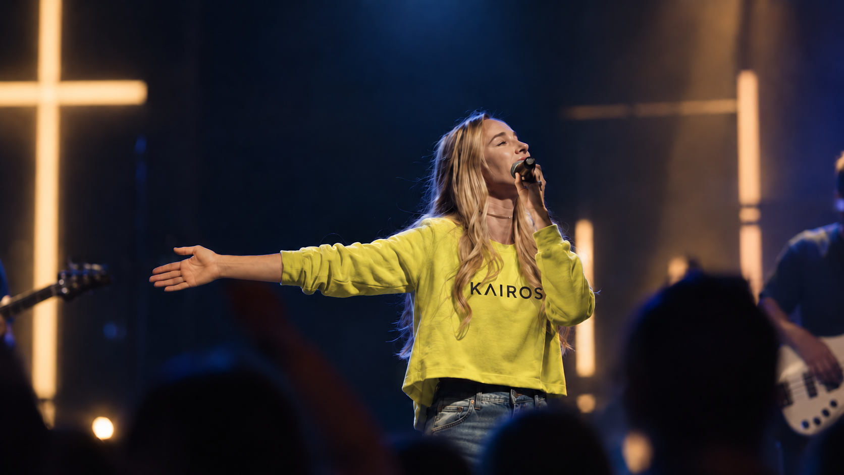 Shalise Marie Catir singing in a Kairos yellow crewneck under the stage cross